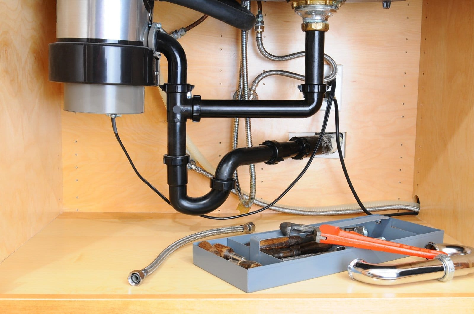 Under-sink plumbing with tools indicating repair or maintenance work.