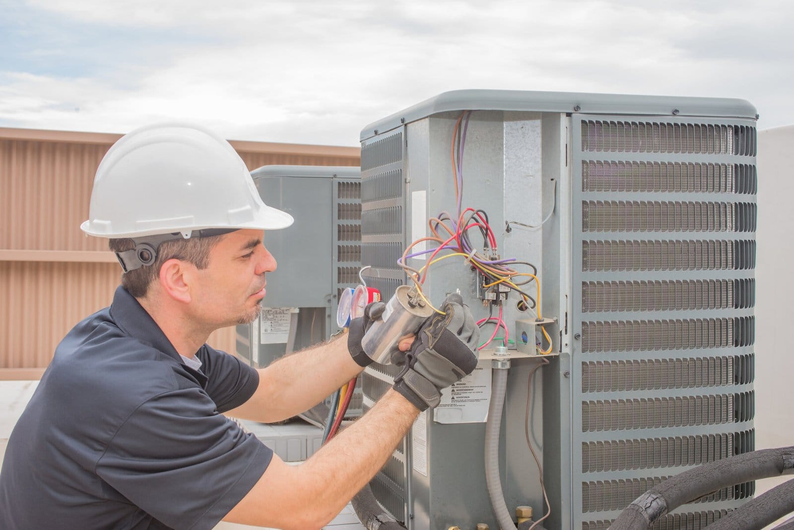Technician servicing an outdoor air conditioning unit.