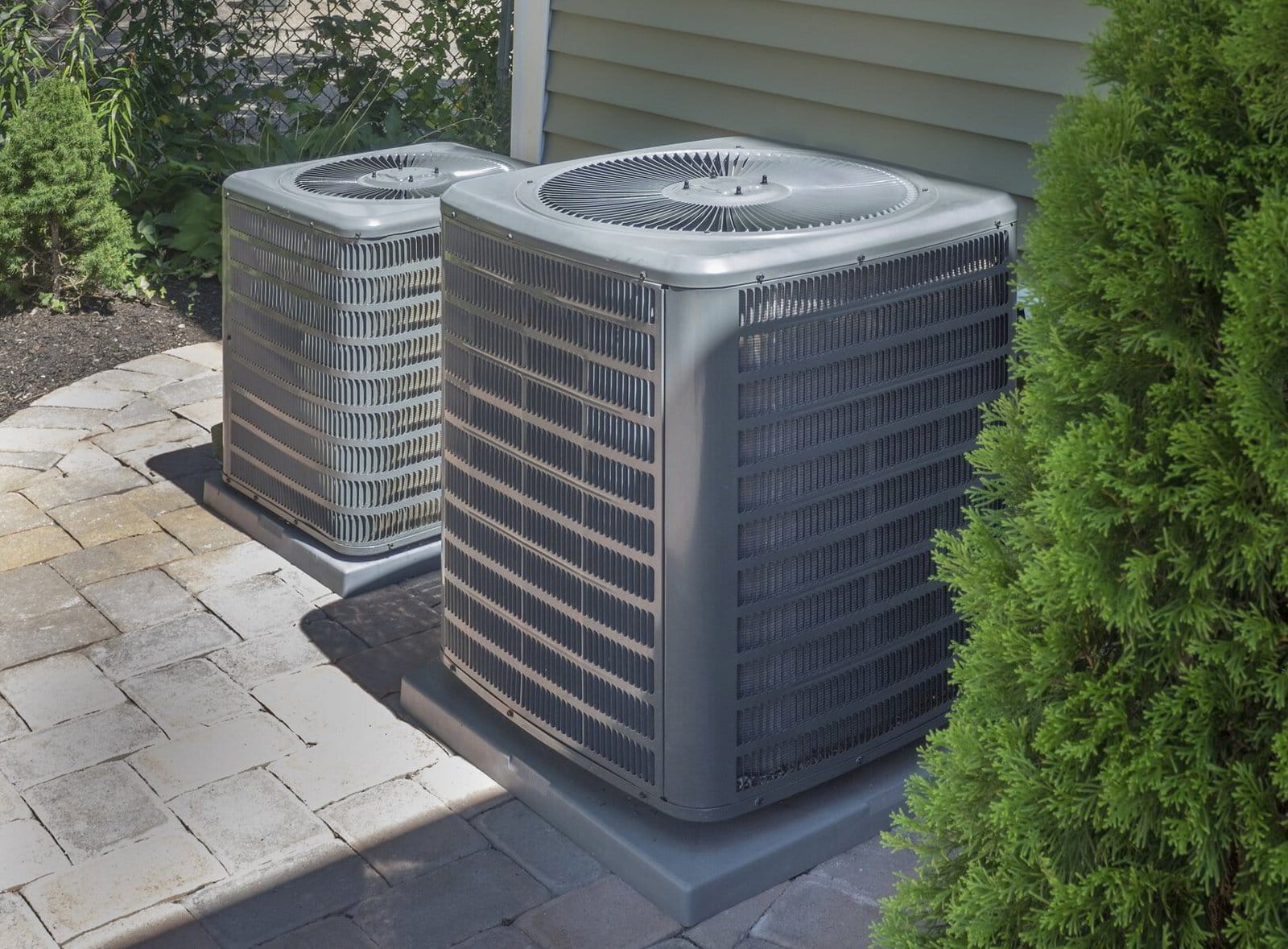 Two residential central air conditioning units outside a home.