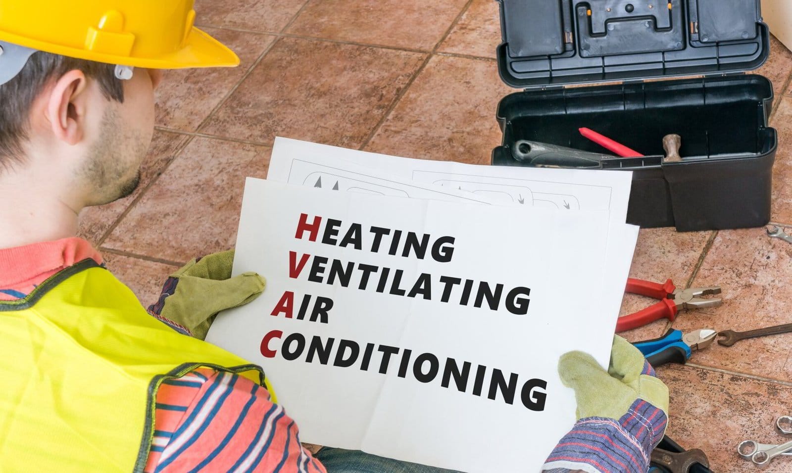 Technician studying a heating, ventilating, and air conditioning diagram with tools nearby.
