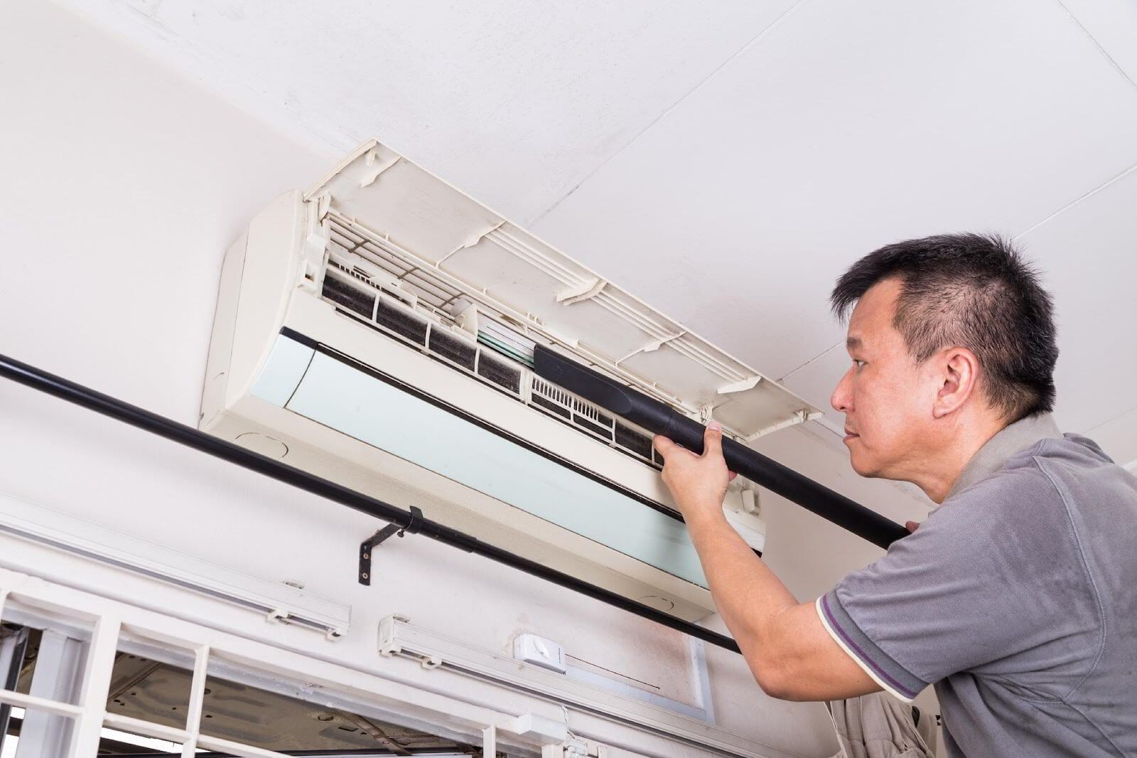 Man performing maintenance on an air conditioning unit.