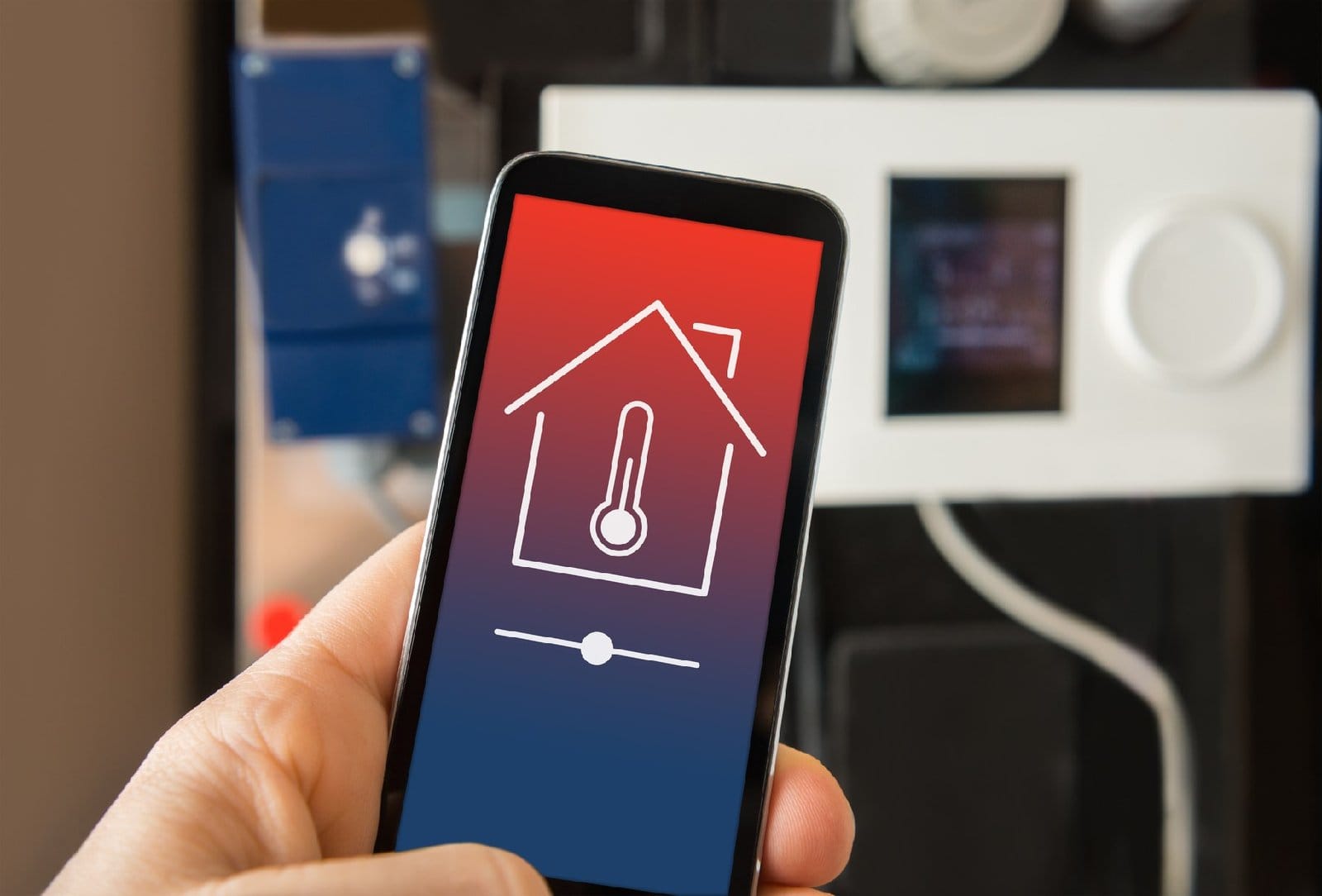 Person using a smartphone to control a smart thermostat at home.