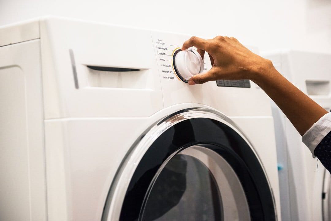 Person setting a washing machine cycle.