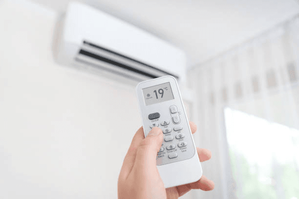 Person using a remote control to set an air conditioner to 19 degrees celsius.