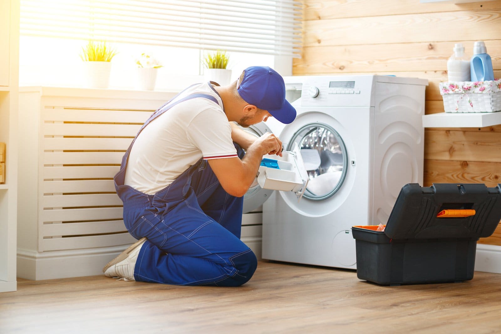 Repair technician examining a washing machine in a laundry room.