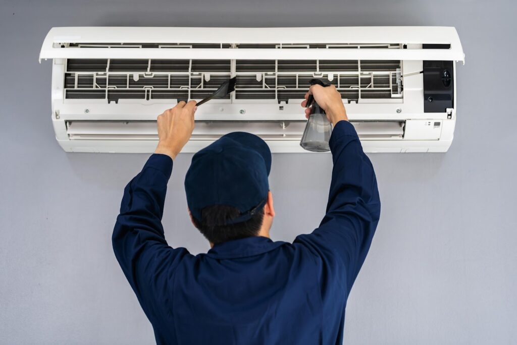 A man fixing an air conditioner on a gray background.
