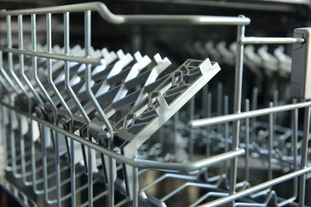 Close-up of dishwasher rack tines with chipped coating and exposed metal, highlighting areas prone to rust before recoating.
