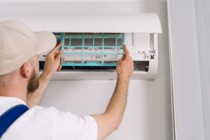 HVAC professional installing a clean air filter into a wall-mounted ductless mini-split air conditioner