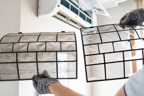 Side-by-side comparison of a heavily soiled, dust-clogged air filter next to a clean replacement filter in front of a mini-split AC unit